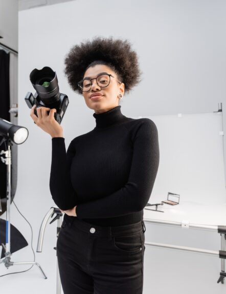 positive african american content maker in black turtleneck and eyeglasses standing with