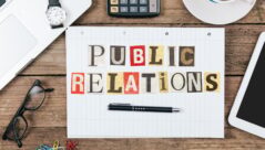 Public Relations title from newspaper cutout letters on paper notepad
